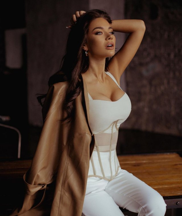 Яна Кошкина в белом платье и коричневой куртке