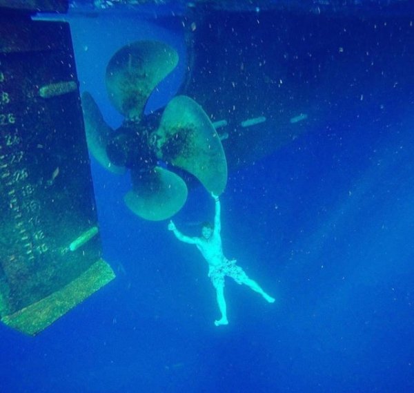 Пловец, держащийся за гигантский гребной винт подводной лодки